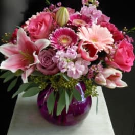 Pink mixed bouquet in a purple glass vase