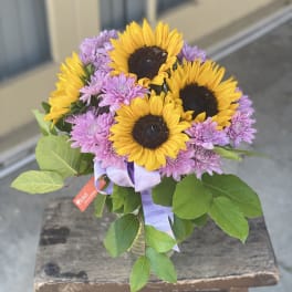 Bouquet of sunflowers and purple chrysanthemums tied with a lavender ribbon