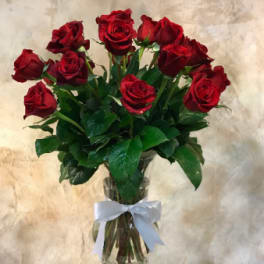 Red roses in a clear glass vase tied with a white ribbon