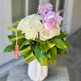 White roses and pink orchids in a white vase