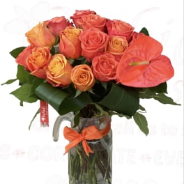 Bouquet of orange and coral roses in a glass pitcher vase