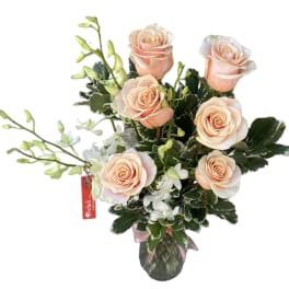 Peach roses with white orchids in a glass vase