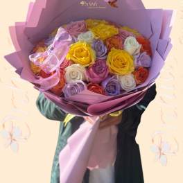 Bouquet of multicolored roses wrapped in purple paper with a pink ribbon