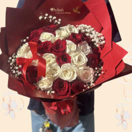 Bouquet of red and white roses wrapped in red paper with a ribbon