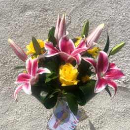Bouquet of pink lilies and yellow roses in a glass vase