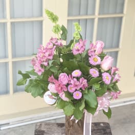 Pink roses and alstroemeria in a decorative vase with ribbon
