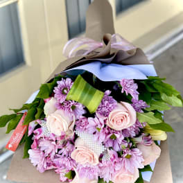 Bouquet of pink roses and purple daisies wrapped in brown paper