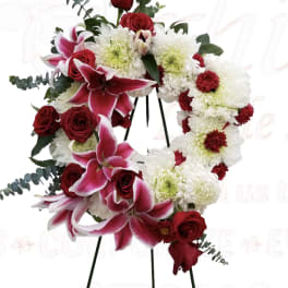 Heart-shaped floral wreath with red roses, pink lilies, and white chrysanthemums
