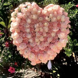 Heart-shaped pink rose and carnation standing spray on a metal easel