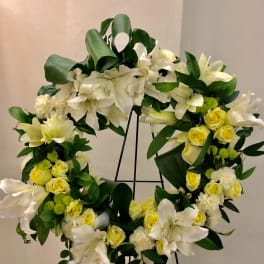 White and yellow floral wreath on a black stand