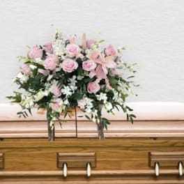 Pink and white floral spray on a wooden casket