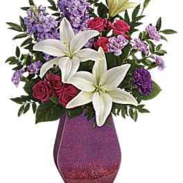 Bouquet of white lilies, pink roses, and purple flowers in a magenta vase