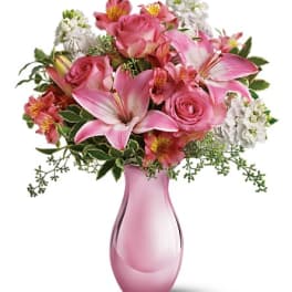 Pink roses and lilies arranged in a pink glass vase