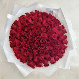 Round bouquet of red roses wrapped in white paper