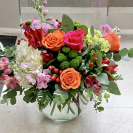 Mixed bouquet of roses, hydrangea, and pink flowers in a glass vase