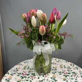 Tulip arrangement in a glass vase with a white ribbon bow