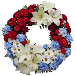 Circular wreath of red and blue carnations with white lilies and daisies