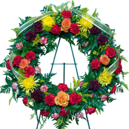 Circular floral wreath on a stand with red, yellow, and orange flowers