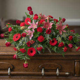 Red and pink floral arrangement with lilies, roses, and gerbera daisies