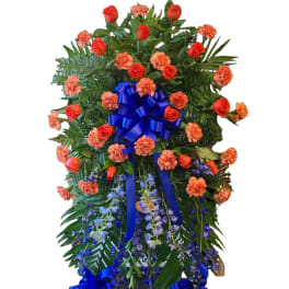 Standing floral spray with red roses, orange carnations, and blue ribbon