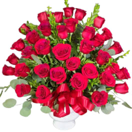 Bouquet of red roses in a white vase with a red ribbon
