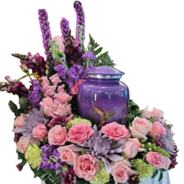 Pink and purple floral arrangement around a purple urn with a hummingbird design