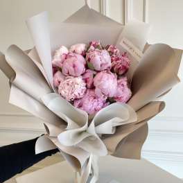Bouquet of pink peonies wrapped in beige and white paper