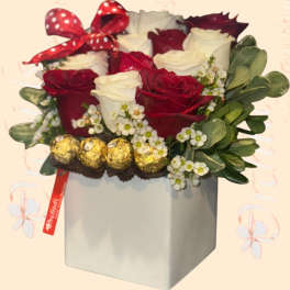 Red and white roses in a gray box with a polka-dot bow and chocolates