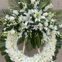 White floral funeral wreath with lilies, roses, and orchids