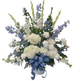White and blue floral arrangement in a white container with a blue ribbon