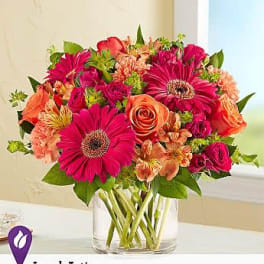 Mixed bouquet of pink and orange flowers in a clear glass vase
