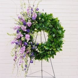 Large purple and green floral wreath on a metal stand