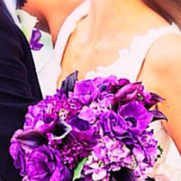 Bride holding a purple bouquet with white ribbon