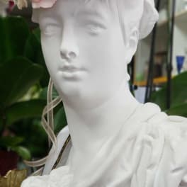 White bust wearing a pastel flower crown with pink and white blooms