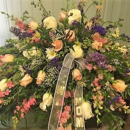 Large mixed floral spray with cream roses and purple accents, tied with a ribbon