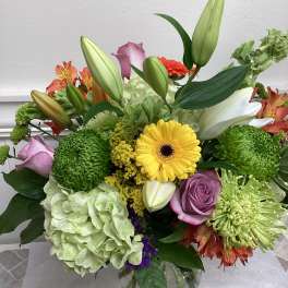 Mixed bouquet in a glass vase with lilies, roses, hydrangea, and chrysanthemums