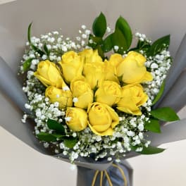 Bouquet of yellow roses with white baby's breath in gray wrapping