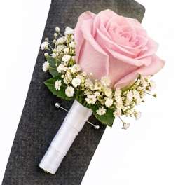 Pink rose boutonniere with white baby's breath on a dark jacket