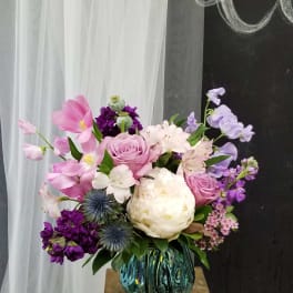 Pink and white floral arrangement in a blue glass vase