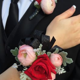 Boutonniere and wrist corsage with red and pink flowers on black ribbon