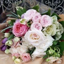 Bouquet of pink, white, and purple roses wrapped in brown paper