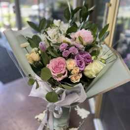 Bouquet of pink, purple, and white flowers wrapped in pale paper