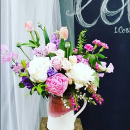 Pink and white mixed flower arrangement in a white pitcher vase