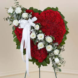 Heart-shaped red floral wreath with white roses and a white ribbon