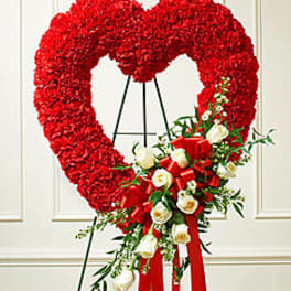 Heart-shaped red floral wreath with white roses and red ribbon