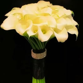 Bouquet of white calla lilies with a glittery band around the stems