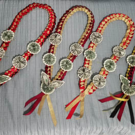 Four braided money garlands with ribbon tassels laid on a bed