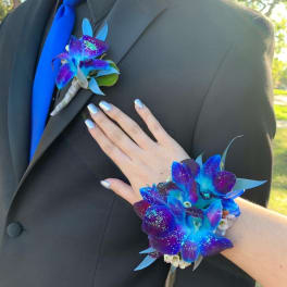 Blue and purple orchid boutonniere and matching wrist corsage on a black suit
