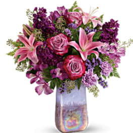 Pink lilies and roses in a tall iridescent vase