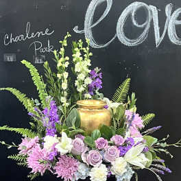 Lavender roses and pink flowers arranged around a gold urn